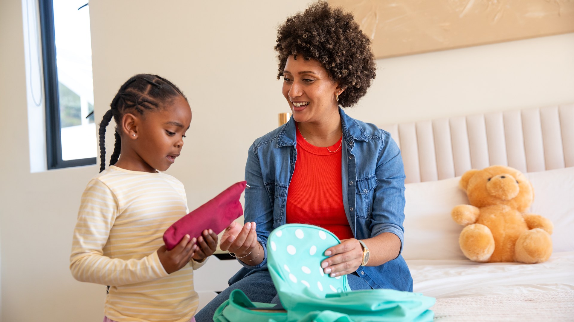 Parent and child packing a summer camp backpack, illustrating pre-camp lice prevention and head checks.