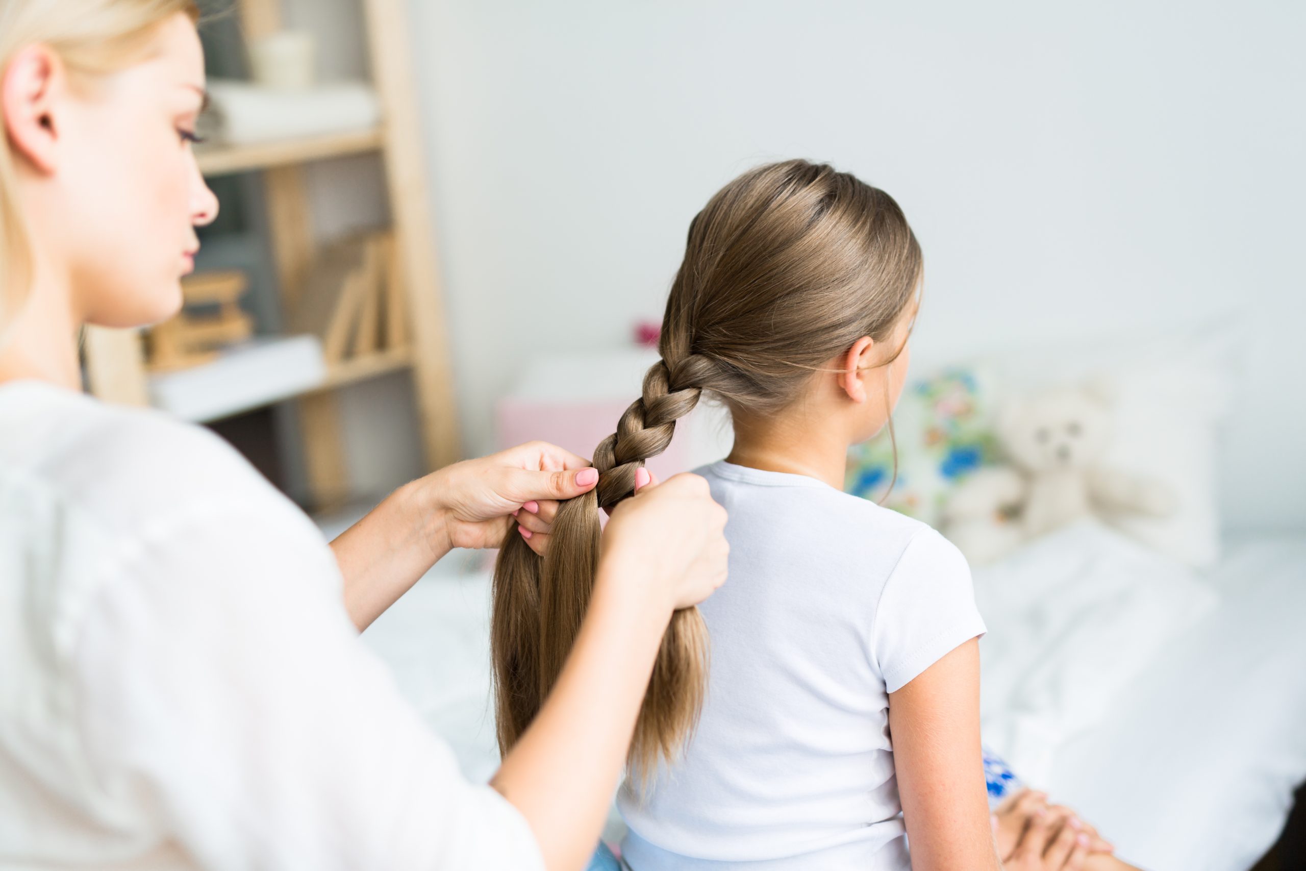Parent braiding a child's long hair, illustrating lice treatment considerations for long, thick, or curly hair.
