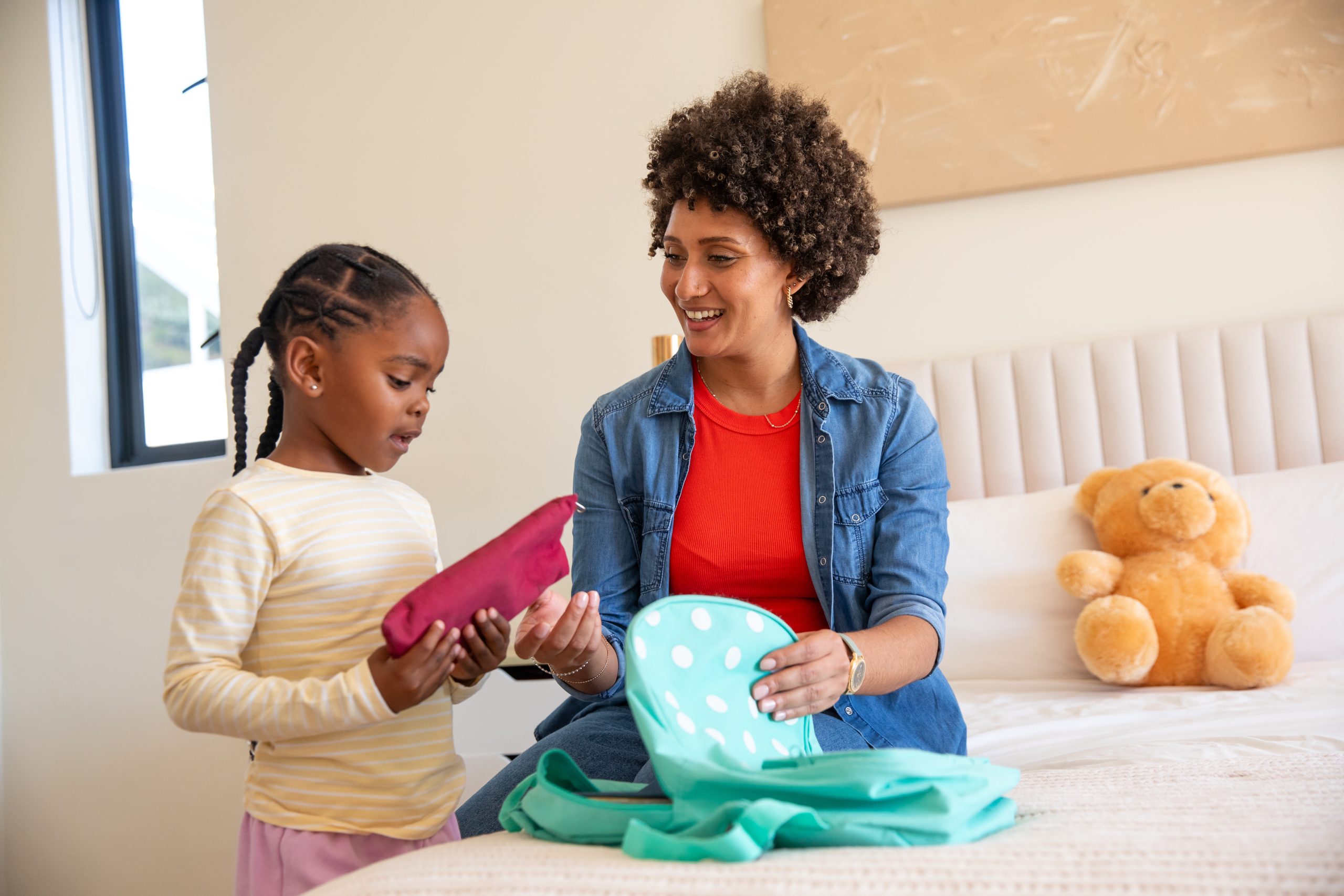 Parent packing a child's backpack on the bed on a school morning after lice treatment
