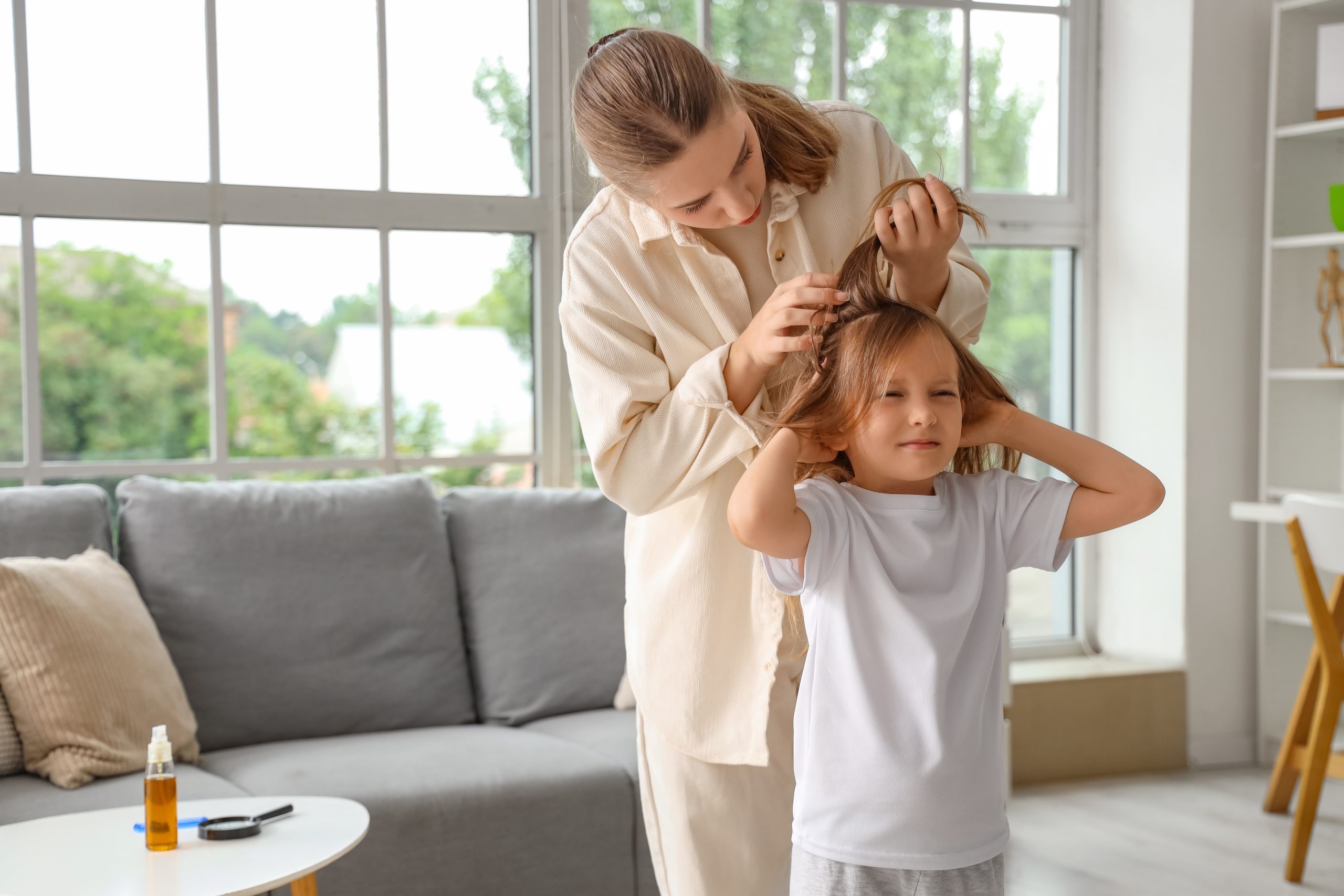 Parent parting a child's hair to check the scalp for signs of lice