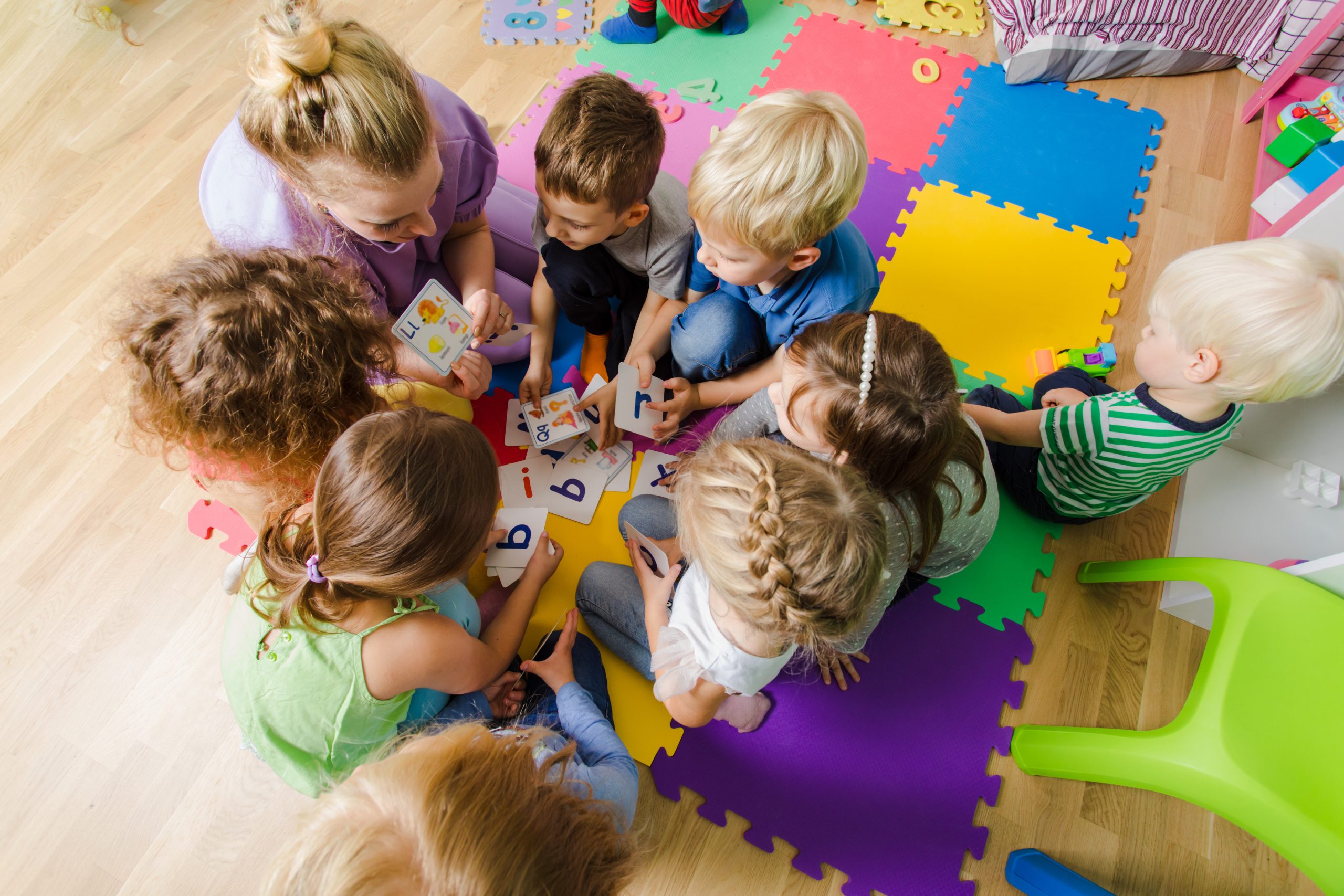 Preschool children gathered with a teacher for a classroom activity, illustrating daycare and preschool close-contact settings