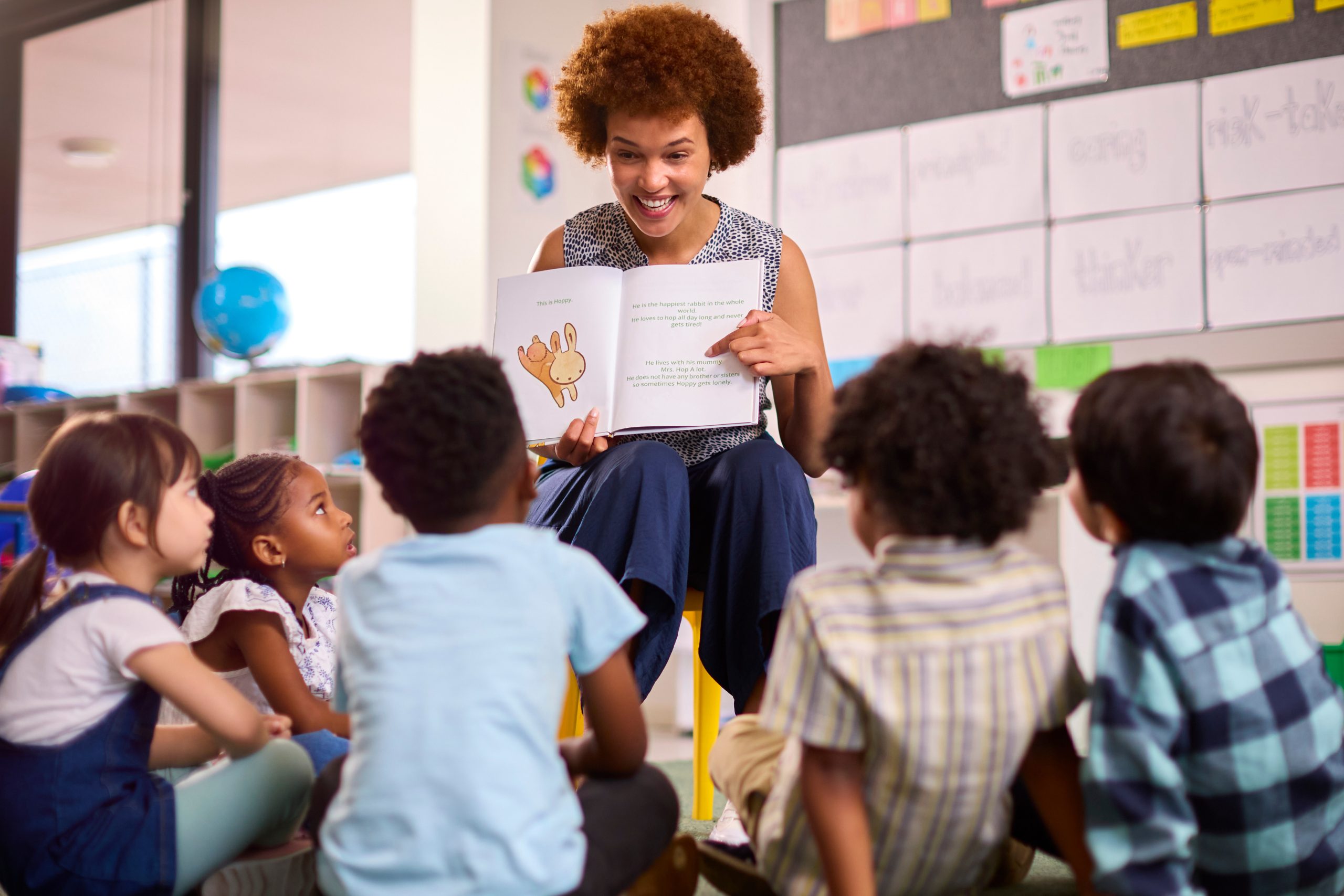 Teacher reading to elementary students seated on a classroom floor, illustrating school education presentations