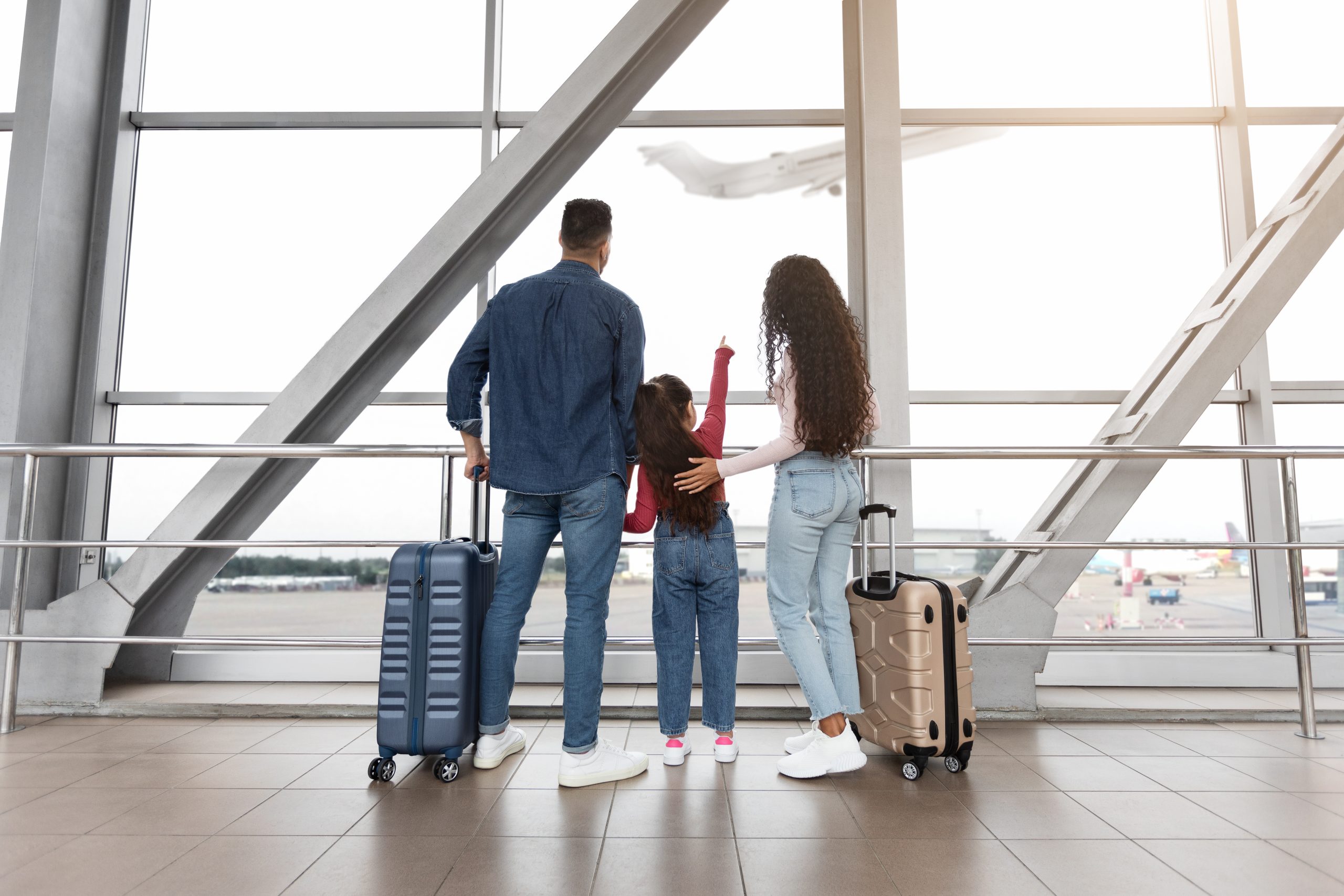 Family watching airplanes from an airport window, illustrating holiday travel and head lice exposure.