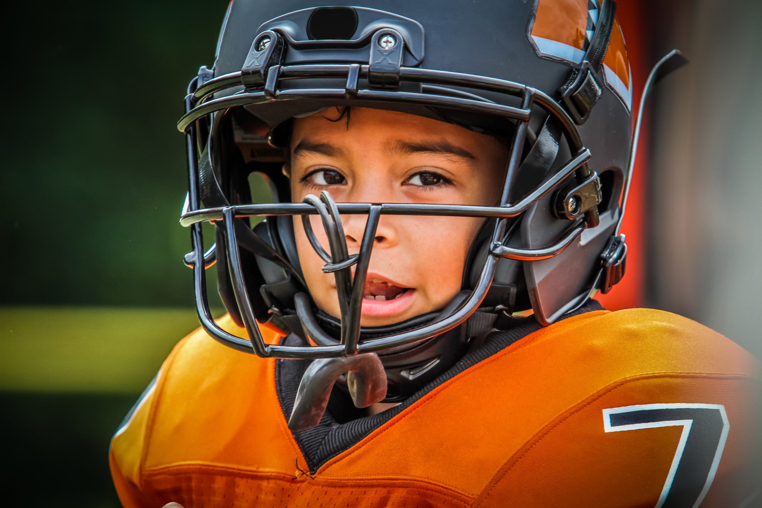 Youth football player wearing a helmet, illustrating sports helmets and head-to-head contact transmission risk