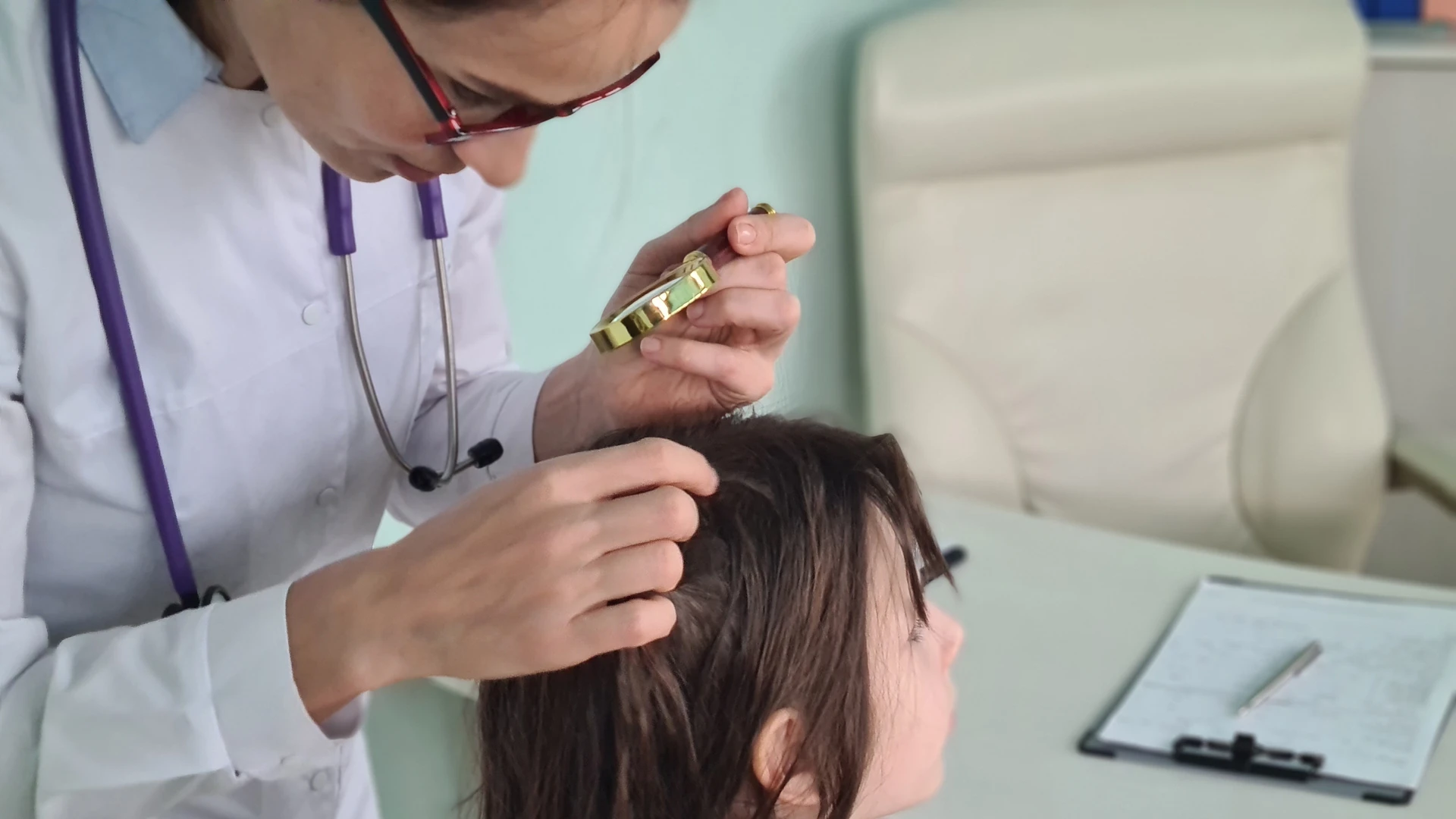 Person in a white coat inspecting parted hair with a magnifying glass