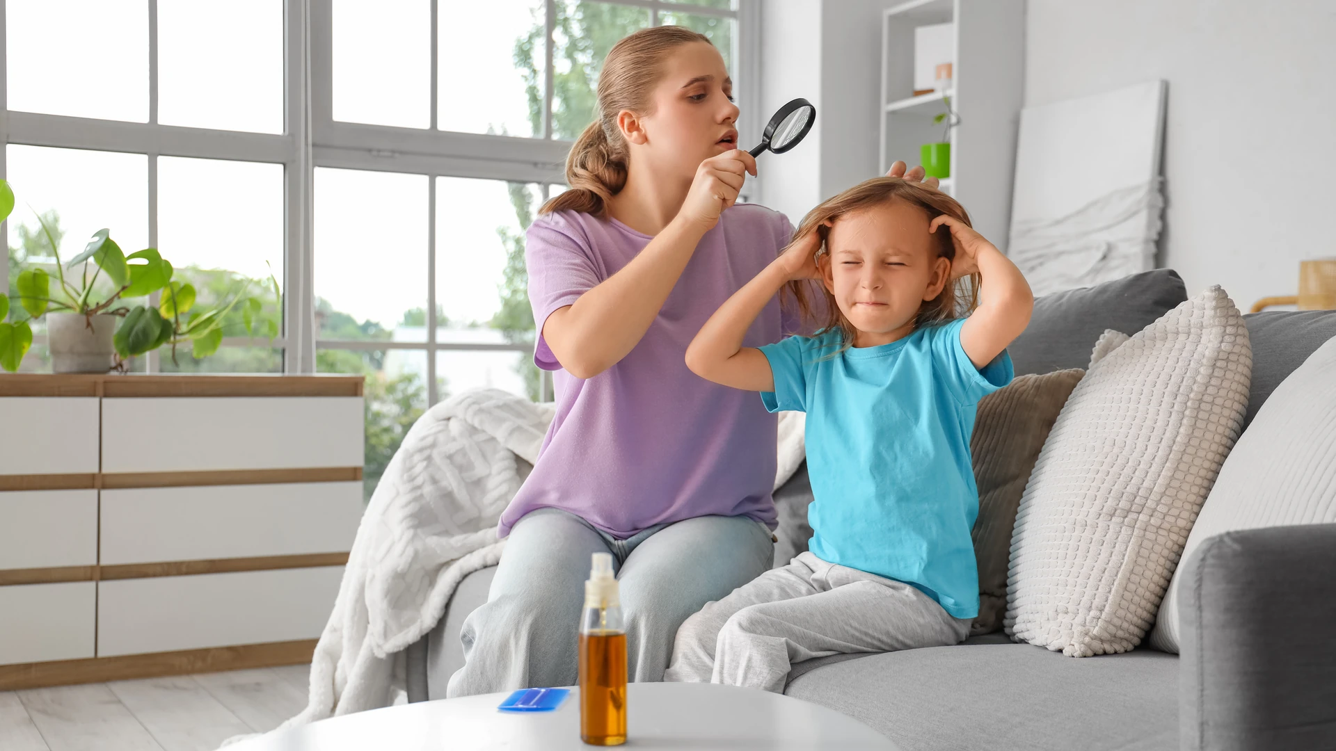 Person holding a magnifying glass near another person's hair on a sofa
